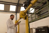 Robotics engineer using digital tablet in warehouse — Stock Photo