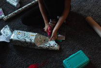 Bassa sezione di donna taglio carta regalo a casa — Foto stock