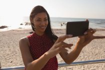 Mujer feliz tomando selfie en el teléfono móvil en el paseo marítimo - foto de stock
