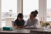Grandmother and granddaughter drawing sketch on table at home — Stock Photo