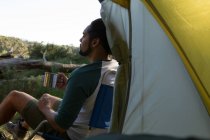 Homem tomando café perto da tenda na floresta — Fotografia de Stock