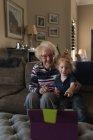 Großmutter und Enkelin telefonieren im heimischen Wohnzimmer mit digitalem Tablet — Stockfoto