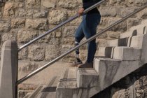 Низкая часть женщины-инвалида спускается по лестнице — стоковое фото