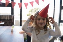 Chica feliz en sombrero de fiesta en casa - foto de stock