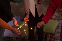 Seção intermediária de grupo de amigos se divertindo com sparklers — Fotografia de Stock