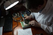 Robotics engineer assembling circuit board at desk in warehouse — Stock Photo