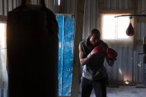 Boxeur masculin déterminé pratiquant la boxe dans un studio de fitness — Photo de stock