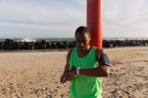 Чоловіча спортсмен, використовуючи smartwatch недалеко від пляжу сонячний день — стокове фото