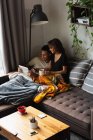 Пара використовує мобільний телефон і цифровий планшет, маючи каву на дивані у вітальні вдома — стокове фото