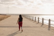 Вид сзади на женщину-инвалида, идущую по набережной — стоковое фото