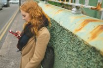 Rothaarige Frau benutzt Handy in einer Gasse — Stockfoto