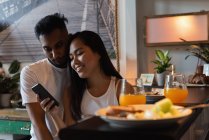 Couple using mobile phone in kitchen at home — Stock Photo