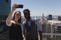 I colleghi d'affari che prendono selfie con mobile a terrazza in ufficio — Foto stock