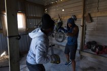Trainer trainiert entschlossenen Boxer im Boxclub — Stockfoto
