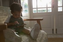 Enfant utilisant un téléphone portable à la maison — Photo de stock
