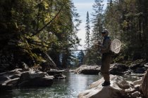 Pescatore pesca a mosca nel fiume in una giornata di sole — Foto stock