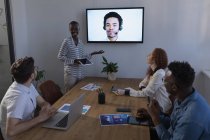 Gente de negocios interactuando a través de videollamadas en la oficina - foto de stock