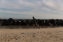 Vista laterale dell'atleta maschile che fa jogging vicino alla spiaggia — Foto stock