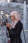 Hijab-Frau überprüft Fotos in Digitalkamera auf Balkon — Stockfoto