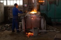Trabajador masculino mudando metal en taller de fundición - foto de stock