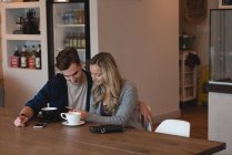 Junges Paar benutzt Handy in Café — Stockfoto