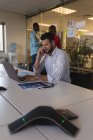Виконавчий директор бізнесу розмовляє на мобільному телефоні під час використання ноутбука в офісі — стокове фото