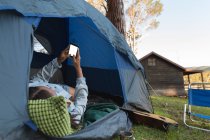 Frau benutzt Handy im Zelt auf Campingplatz — Stockfoto