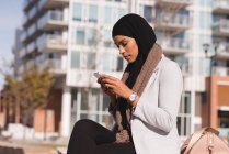 Vue latérale de la femme hijab utilisant le téléphone mobile dans la ville — Photo de stock