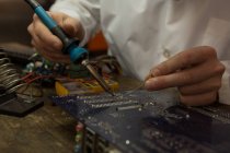 Close-up of robotics engineer assembling circuit board at desk — Stock Photo