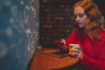 Femme rousse utilisant un téléphone portable dans le café — Photo de stock