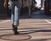 Partie basse de la femme marchant en ville par une journée ensoleillée — Photo de stock