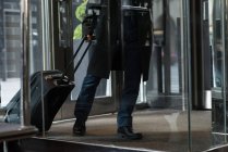 Sección baja de hombre de negocios que entra en el hotel con equipaje - foto de stock
