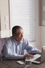 Senior man using laptop on table at home — Stock Photo