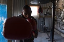 Primer plano del boxeador masculino practicando boxeo en un gimnasio - foto de stock
