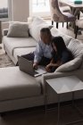 Дід і онука використовують ноутбук на дивані у вітальні вдома — стокове фото