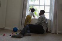 Pai e filho sentados perto da janela em casa — Fotografia de Stock