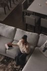 Старшая женщина разговаривает по мобильному телефону на диване в гостиной на дому — стоковое фото