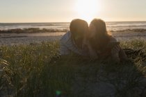 Пара цілується на пляжі під час заходу сонця — стокове фото