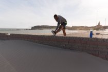 Atleta masculino que se estende perto da praia em um dia ensolarado — Fotografia de Stock