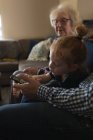 Родина багатьох поколінь використовує мобільний телефон на дивані у вітальні вдома — стокове фото