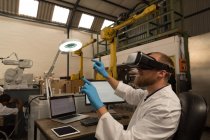 Robotics engineer using virtual reality headset at desk in warehouse — Stock Photo
