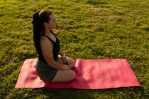 Vista laterale del jogger femminile che fa yoga nel parco — Foto stock