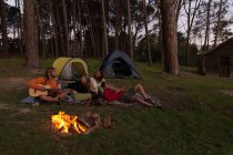 Grupo de amigos se divertindo perto da fogueira no acampamento — Fotografia de Stock