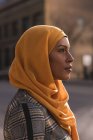 Pensativo hijab mujer de pie en la ciudad - foto de stock