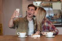 Jovem casal tomando selfie no café — Fotografia de Stock