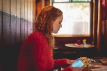 Donna rossa che utilizza tablet digitale in caffè — Foto stock