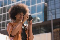 Woman clicking photo with digital camera in city — Stock Photo