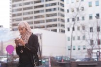Hijab woman using mobile phone in city — Stock Photo