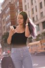 Улыбающаяся женщина с мобильного телефона в городе — стоковое фото