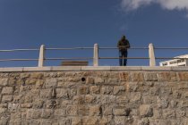 Low angle view of man leaning on promenade railing — Stock Photo